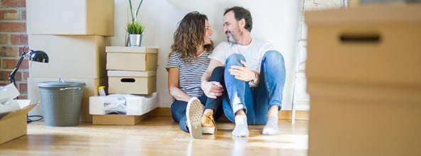 Couple sitting on the floor of their new home with boxes around them
