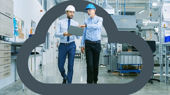 2 facilities managers walking through a factory looking at a laptop