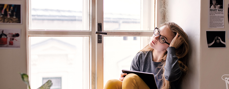 Blonde woman sitting on a windowsill on a tablet