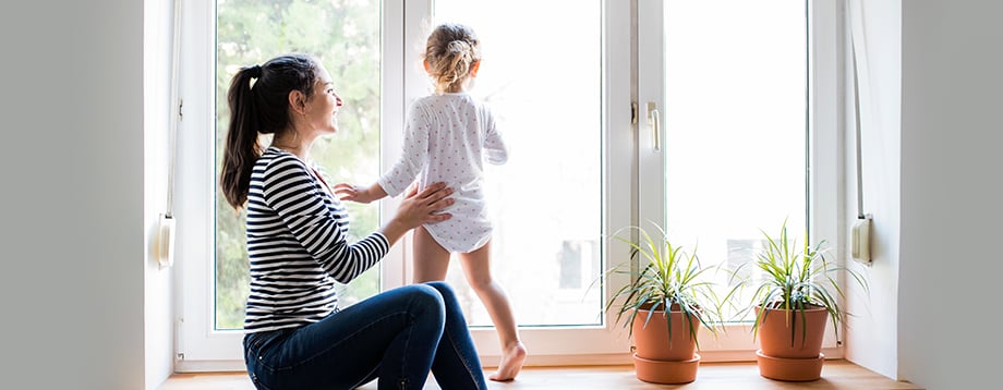 Mother with her young daughter by large windows
