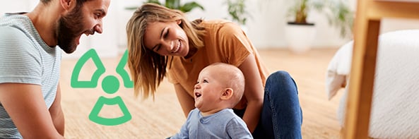 Mother, father and smiling baby playing with a Radon symbol overlayed