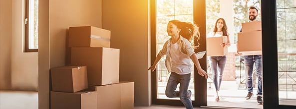 Family moving into a new home carrying boxes