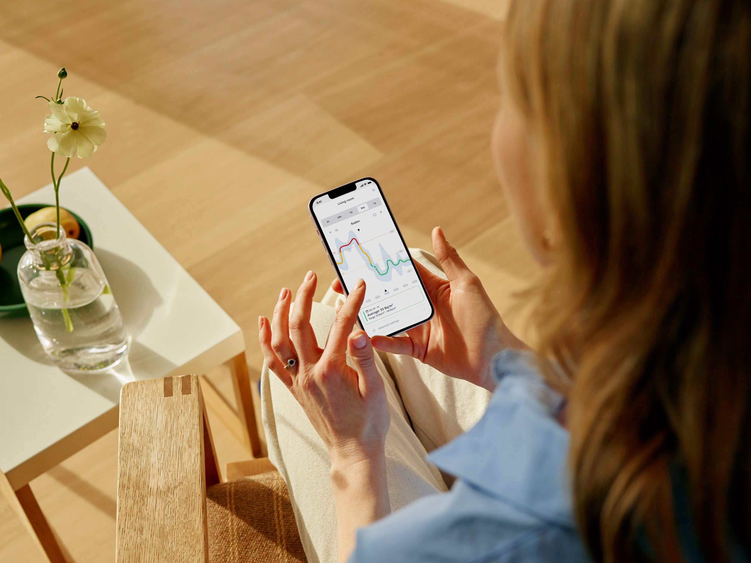 Airthings app showing live radon reading and indoor air quality dashboard in a living room setting